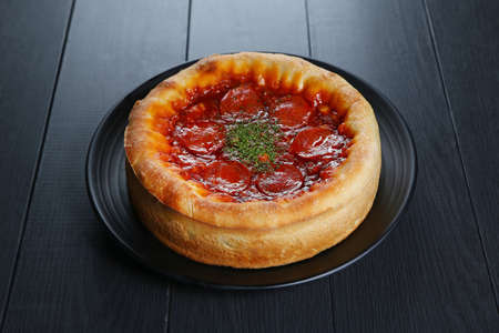 Chicago style of pizza with red chili on black plateの写真素材