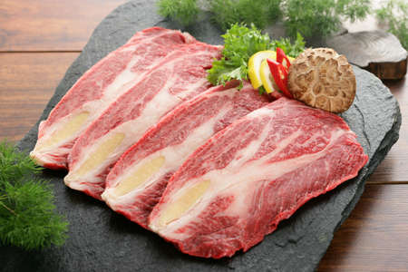 Sliced fresh beef on stone plate with mushroom and lemon