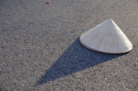 Vietnamese traditional leaf hat with shadow on the hot road surfaceの写真素材