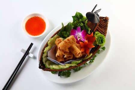 Vietnamese fried spring rolls on bamboo tray with sliced cucumber, salad and chili sauceの写真素材