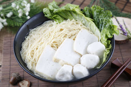 Traditional chinese bowl of wanton vermicelli with fish ball and paste on the table in restaurant