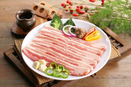 Sliced fresh Pork meat on white plate with herbs and chiliの写真素材