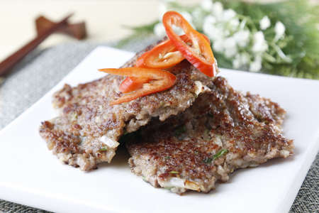 Grilled meat on white plate with sliced chili
