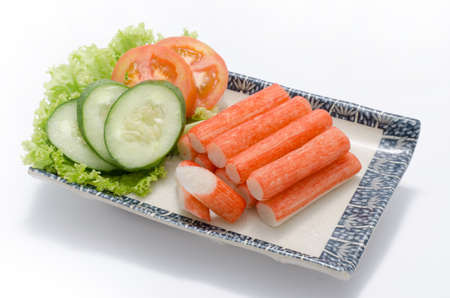 Crabmeat sticks with sliced cucumber and tomato on plateの写真素材