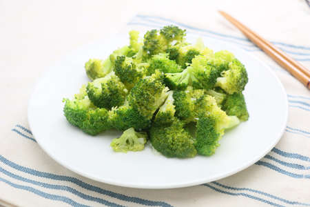 Steamed green Broccoli on white plate in restaurantの写真素材