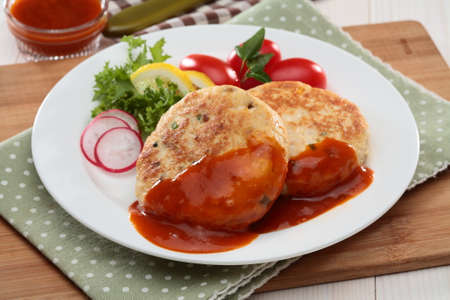 Homemade precooked tofu steaks with tomato, radish, lemon, lettuce and chili sauce on white plateの写真素材