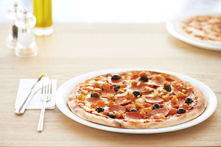 Olive pizza on white plate in the restaurantの写真素材
