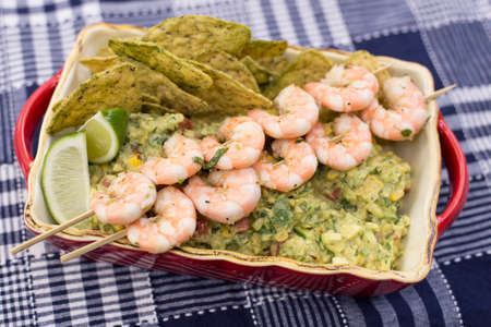 The finished dish of roasted corn guacamole with shrimp skewers and corn chipsの写真素材