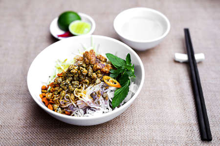 Vietnamese rice vermicelli with fried clams in white bowl with herbs and lemonの写真素材