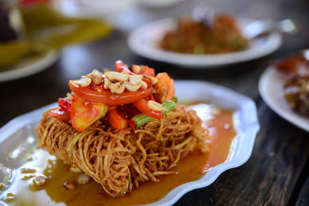 Fried dried sliced squid with sauce and tomato on white plateの写真素材