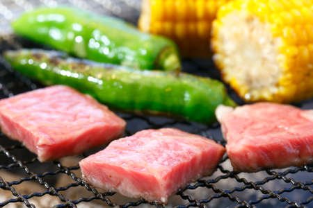 Grilling cubed pork meat with green chili and corn on hot charcoalの写真素材