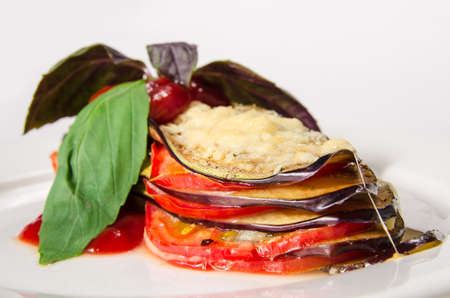 Fried sliced eggplant with chili sauce and herbs on white plate backgroundの写真素材
