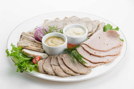 Sliced meat plateau ham with sauces and salad on white plateの写真素材