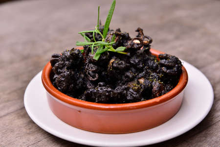 Fried baby octopus on white plate on wooden table in restaurantの写真素材