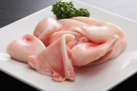 Fresh raw Pig cartilage meat with cumin herbs on white platterの写真素材