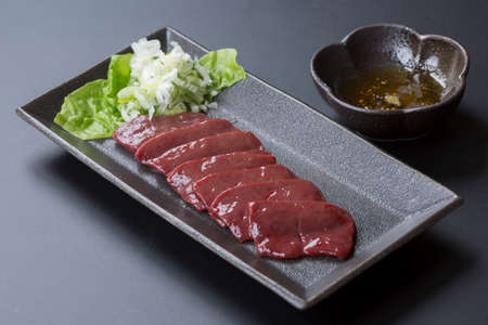 Beef roast liver with Sesame oil, Garlic soy sauce and lettuce on black dishの写真素材