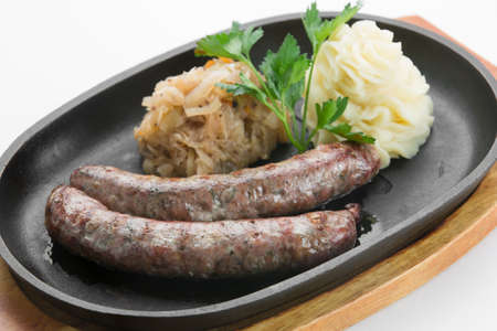 From turkey veal roasted with paprika sausages in black pan on wooden cutting boardの写真素材