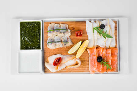 Fish plate with lemon, olive, chili and sauce on white backgroundの写真素材