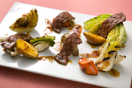 Beef roasted with vegetables cabbage, sweet potato, lotus and carrot on white plateの写真素材