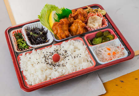 Faint fried chicken lunch with fried tempura, chili and plain rice in bento boxの写真素材