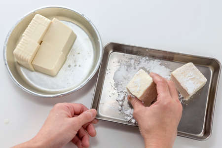 Salting fresh tofu by hands in the kitchenの写真素材