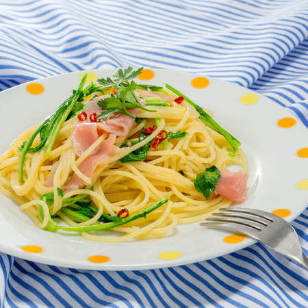 Pasta noodle with sauteed pork and vegetables on the tableclothの写真素材