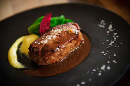 Roasted Beef Tenderloin with sauce and lettuce on black platterの写真素材