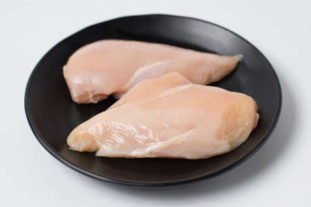 Fresh chicken breast fillets on black dishの写真素材