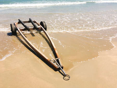 The wheelbarrow on the beach with sea wave foamの写真素材
