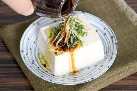 Special tofu cake with oil and onion on white platterの写真素材