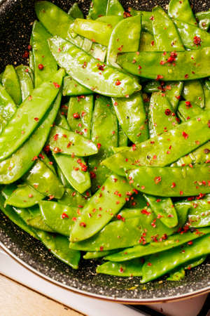 Snow peas with herbs and lemon in black panの写真素材