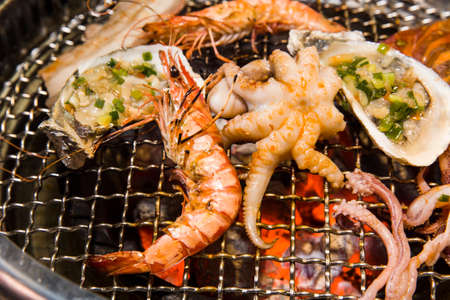 Grilling seafood of shrimp, octopus and oysters on hot charcoalの写真素材