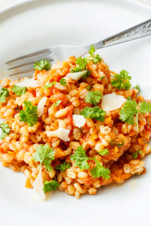 Pearl barley and tomato stew on white platterの写真素材