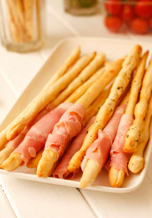 Italian bread sticks grissini with pork and hamの写真素材