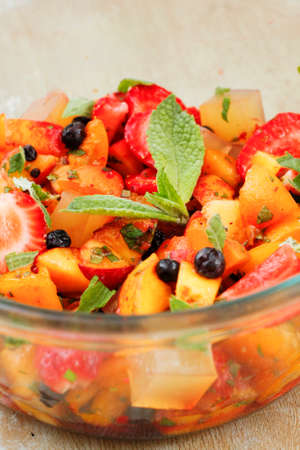 Berries and fruit salad with slices of jelly and mint sauceの写真素材