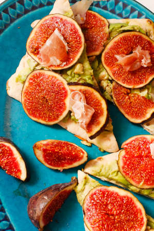Pizza  with fresh figs, avocados and maple syrup on platterの写真素材