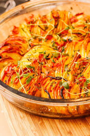 Baked crispy fries with herbs in glass bowl on wooden boardの写真素材