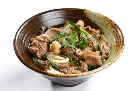 Bowl of ramen beef noodle with herbs on white background