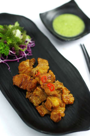 Braised pork with chili sauce and salad on black platterの写真素材