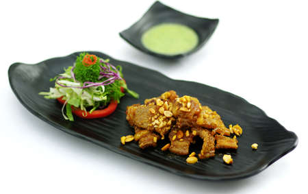 Braised pork with chili sauce and salad on black platterの写真素材