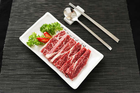 Sliced fresh beef with cummin and chili on white platterの写真素材