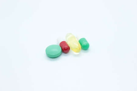 Multi-colored pill capsules are located on a white background