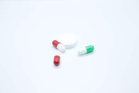 Multi-colored pill capsules are located on a white background