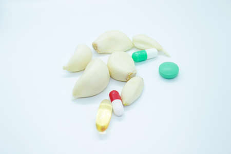 Cloves of garlic pills capsules located on a white backgroundの写真素材