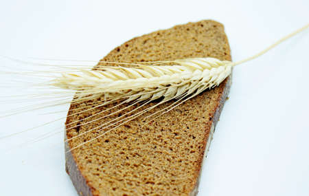 A piece of bread and rye spike located on a white background