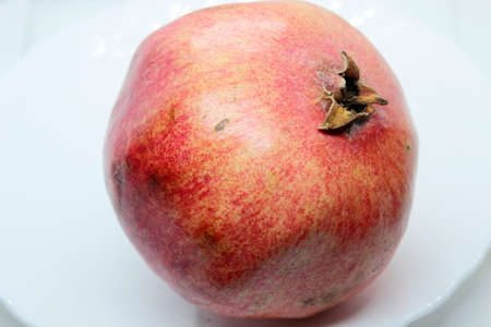 Ripe beautiful red pomegranate is located on whiteの写真素材