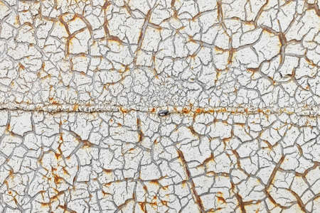 White cracked paint is applied to a rusty surfaceの写真素材