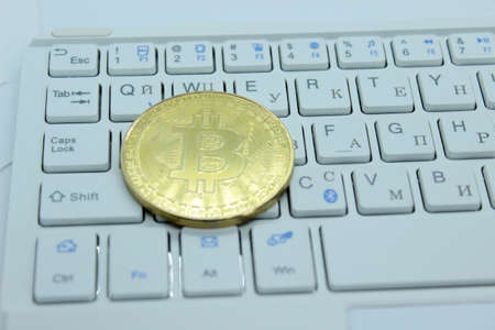 Gold Bitcoin located on a white keyboard, cryptocurrency
