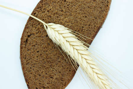 A piece of black bread and a colossus of rye is located on a white backgroundの写真素材