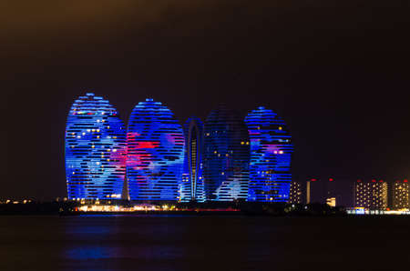 Scenic night view of buldings on Phoenix island with backlight and reflection in a sea in Sanya, Hainan, Chinaのeditorial素材